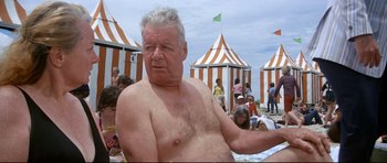 Movie still from “Jaws” (1975), directed by Steven Spielberg – An older man is sitting on the beach; Medium shot, Low angle