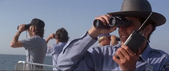 Movie still from “Jaws” (1975), directed by Steven Spielberg – A group of people standing on top of a boat looking through binoculars; Close Up shot, Low angle