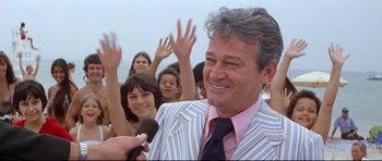 Movie still from “Jaws” (1975), directed by Steven Spielberg – A group of people with microphones in front of a man in a striped suit; Medium shot, Over the shoulder angle