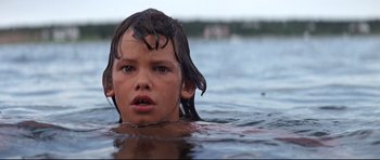 Movie still from “Jaws” (1975), directed by Steven Spielberg – A young boy swimming in a body of water; Close Up shot, Low angle