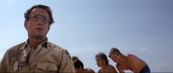 Movie still from “Jaws” (1975), directed by Steven Spielberg – A group of young men standing next to each other on the beach; Close Up shot, Low angle