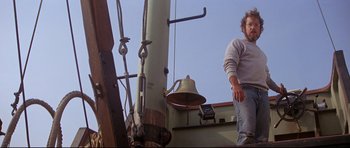 Movie still from “Jaws” (1975), directed by Steven Spielberg – A man standing next to a bell on top of a building; Medium shot, Low angle