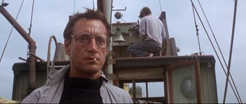 Movie still from “Jaws” (1975), directed by Steven Spielberg – A man with a cigarette in his mouth and a bell on a boat; Close Up shot, Low angle