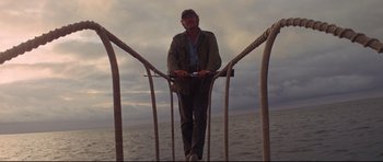Movie still from “Jaws” (1975), directed by Steven Spielberg – A man standing on top of a boat in the water; Wide shot, Low angle