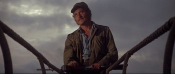 Movie still from “Jaws” (1975), directed by Steven Spielberg – A man with a beard and a hat is holding a wrench; Medium shot, Low angle