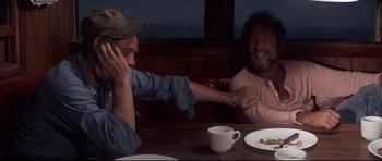 Movie still from “Jaws” (1975), directed by Steven Spielberg – Two men sitting at a table with a plate of food; Medium shot, Over the shoulder angle