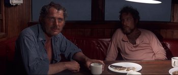Movie still from “Jaws” (1975), directed by Steven Spielberg – Two men sitting at a table with a plate of food; Medium shot, Over the shoulder angle