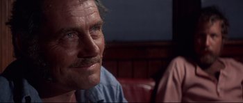 Movie still from “Jaws” (1975), directed by Steven Spielberg – An older man with a mustache sitting on a red couch; Close Up shot, Over the shoulder angle