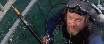 Movie still from “Jaws” (1975), directed by Steven Spielberg – A man in the water holding onto a pipe; Close Up shot, Overhead angle