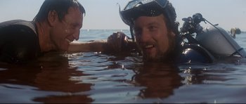 Movie still from “Jaws” (1975), directed by Steven Spielberg – Two men in the water holding each other's hand; Close Up shot, Low angle
