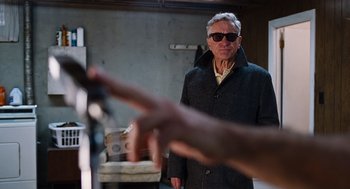 Movie still from “Joy” (2015), directed by David O. Russell – An older man wearing sunglasses and a coat; Medium shot, Over the shoulder angle