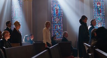 Movie still from “Joy” (2015), directed by David O. Russell – A group of people sitting in a room with a stained glass window; Wide shot, Low angle