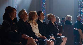 Movie still from “Joy” (2015), directed by David O. Russell – A group of people sitting next to each other in front of a stained glass window; Wide shot, High angle