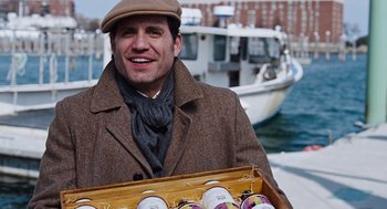 Movie still from “Joy” (2015), directed by David O. Russell – A man holding a box full of drinks; Medium shot, Over the shoulder angle