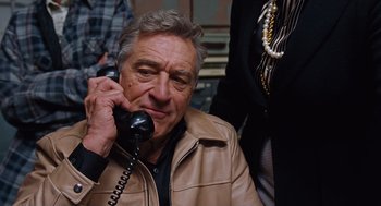 Movie still from “Joy” (2015), directed by David O. Russell – An older man talking on a phone while wearing a leather jacket; Close Up shot, High angle
