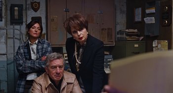 Movie still from “Joy” (2015), directed by David O. Russell – A group of people standing in a room; Medium shot, Over the shoulder angle
