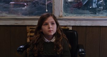 Movie still from “Joy” (2015), directed by David O. Russell – A young girl sitting in a chair in front of a window; Close Up shot, High angle