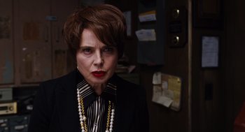 Movie still from “Joy” (2015), directed by David O. Russell – An older woman wearing a black suit and a striped shirt; Close Up shot, Over the shoulder angle