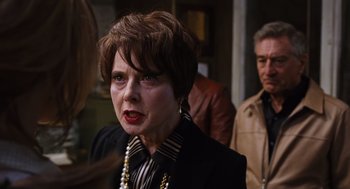 Movie still from “Joy” (2015), directed by David O. Russell – An older woman with short brown hair wearing a black jacket; Close Up shot, Over the shoulder angle