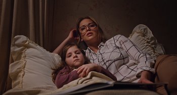 Movie still from “Joy” (2015), directed by David O. Russell – A woman and a child laying in bed; Medium shot, High angle