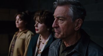 Movie still from “Joy” (2015), directed by David O. Russell – A man and a woman standing next to each other in front of another man; Close Up shot, Over the shoulder angle