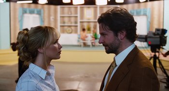 Movie still from “Joy” (2015), directed by David O. Russell – A man and a woman standing next to each other; Close Up shot, Over the shoulder angle