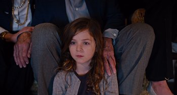 Movie still from “Joy” (2015), directed by David O. Russell – A little girl sitting next to an older man; Medium shot, High angle