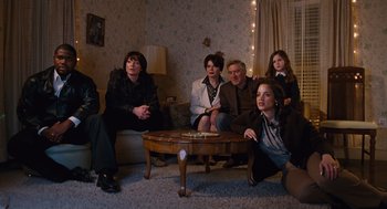 Movie still from “Joy” (2015), directed by David O. Russell – A group of people sitting on a couch in a living room; Wide shot, High angle