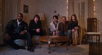 Movie still from “Joy” (2015), directed by David O. Russell – A group of people sitting on a couch in a living room; Wide shot, High angle