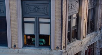 Movie still from “Joy” (2015), directed by David O. Russell – A woman sitting on a window ledge looking out of a window; Extreme Wide shot, High angle