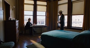 Movie still from “Joy” (2015), directed by David O. Russell – A man and a woman are sitting in front of a window in a bedroom; Wide shot, Low angle