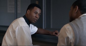 Movie still from “Just Mercy” (2019), directed by Destin Daniel Cretton – A man sitting in front of a window with his hand on his chin; Close Up shot, Over the shoulder angle