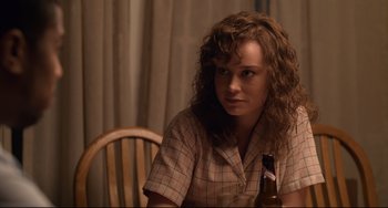 Movie still from “Just Mercy” (2019), directed by Destin Daniel Cretton – A woman sitting at a table with a bottle of beer; Close Up shot, Over the shoulder angle