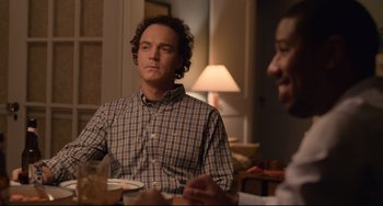 Movie still from “Just Mercy” (2019), directed by Destin Daniel Cretton – A man sitting at a table with another man in the background; Medium shot, Over the shoulder angle