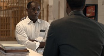 Movie still from “Just Mercy” (2019), directed by Destin Daniel Cretton – A man sitting at a table in front of another man in a suit; Medium shot, Over the shoulder angle
