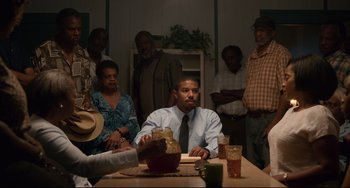 Movie still from “Just Mercy” (2019), directed by Destin Daniel Cretton – A group of people sitting around a table; Wide shot, Over the shoulder angle
