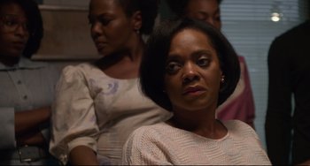 Movie still from “Just Mercy” (2019), directed by Destin Daniel Cretton – Three women are standing in a room and one of them is looking at the camera; Close Up shot, Over the shoulder angle