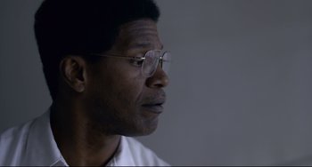 Movie still from “Just Mercy” (2019), directed by Destin Daniel Cretton – A person wearing glasses and a white shirt; Close Up shot, Low angle