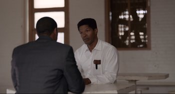 Movie still from “Just Mercy” (2019), directed by Destin Daniel Cretton – Two men sitting at a table talking to each other; Medium shot, Over the shoulder angle