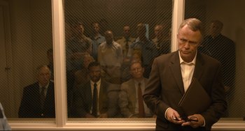 Movie still from “Just Mercy” (2019), directed by Destin Daniel Cretton – A group of men in suits behind a window; Medium shot, Over the shoulder angle