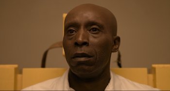 Movie still from “Just Mercy” (2019), directed by Destin Daniel Cretton – A man with a bald head sitting in front of a wall; Close Up shot, Low angle