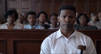 Movie still from “Just Mercy” (2019), directed by Destin Daniel Cretton – A man in a courtroom with other people in the background; Close Up shot, Over the shoulder angle