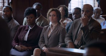 Movie still from “Just Mercy” (2019), directed by Destin Daniel Cretton – A group of people sitting in a court room; Medium shot, Over the shoulder angle