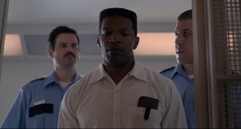 Movie still from “Just Mercy” (2019), directed by Destin Daniel Cretton – A man in a white dress shirt holding a pipe; Close Up shot, Low angle