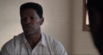 Movie still from “Just Mercy” (2019), directed by Destin Daniel Cretton – A man in a white dress shirt is looking at the camera; Close Up shot, Low angle