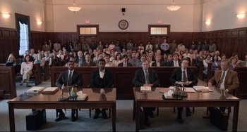 Movie still from “Just Mercy” (2019), directed by Destin Daniel Cretton – A group of men sitting in front of an audience in a courtroom; Wide shot, High angle