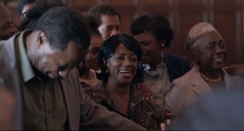 Movie still from “Just Mercy” (2019), directed by Destin Daniel Cretton – A group of people gathered around a woman crying; Medium shot, Over the shoulder angle