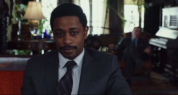Movie still from “Knives Out” (2019), directed by Rian Johnson – A man wearing a suit and tie sitting in front of a window; Close Up shot, Over the shoulder angle