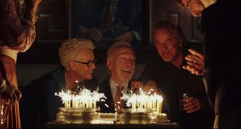 Movie still from “Knives Out” (2019), directed by Rian Johnson – A group of people that are sitting around a cake; Medium shot, High angle