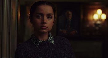 Movie still from “Knives Out” (2019), directed by Rian Johnson – A young woman in a dark room with a painting in the background; Close Up shot, Over the shoulder angle